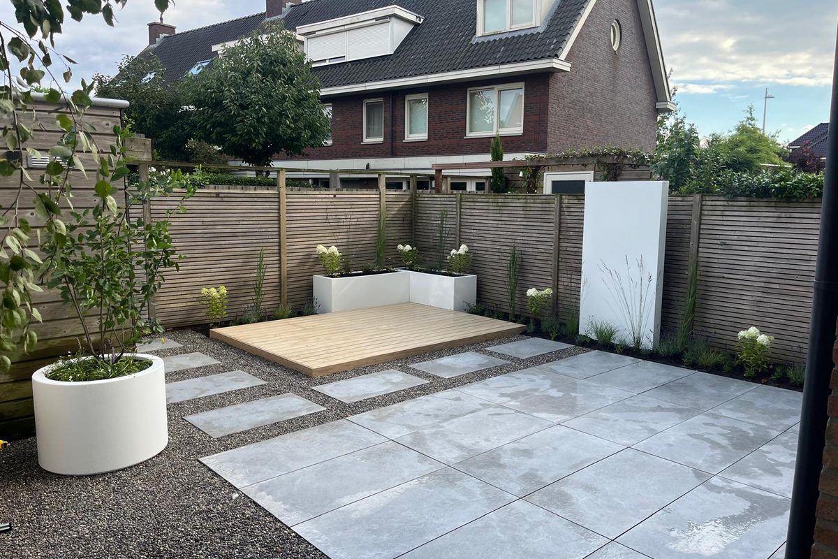 Tuin met witte polyester muren, plantenbakken en een houten vlonder